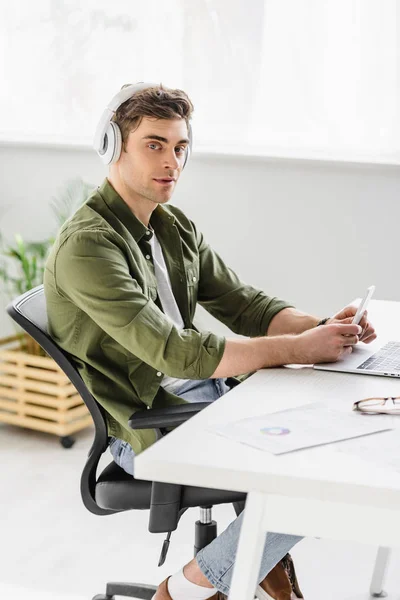 Handsome Businessman Headphones Sitting Table Laptop Holding Smartphone Listening Music — Stock Photo, Image