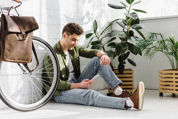 Mann Grünem Hemd Und Jeans Hält Smartphone Der Hand Sitzt — Stockfoto