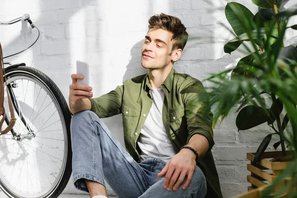 Handsome Man Green Shirt Holding Smartphone Sitting Brick Wall Bicycle — Stock Photo, Image