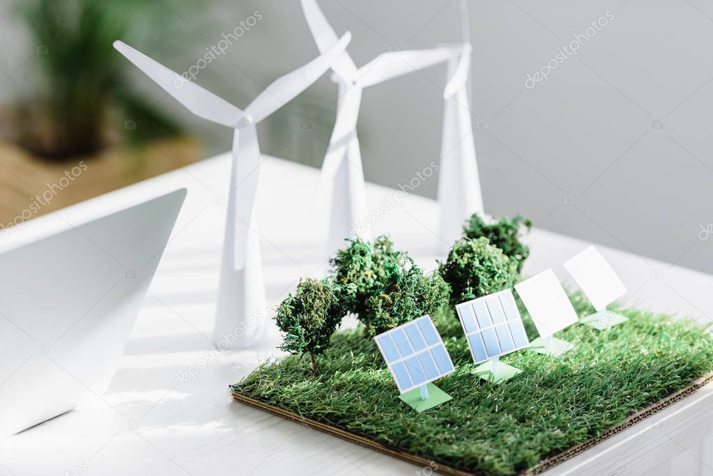 table with trees, windmills and solar panels models on grass in office