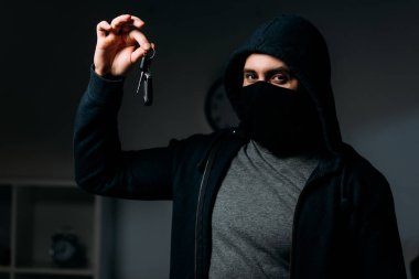 Soyguncu maskesi ve tuşu tutmakta ve kameraya bakarak hoodie