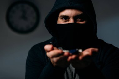 Criminal in hoodie and mask showing keys at camera clipart
