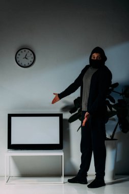 Siyah maskeli elleri boş ekran ile düz ekran TV ile işaret sürpriz hırsız