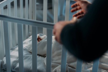 Cropped view of criminal kidnapping newborn child from crib clipart