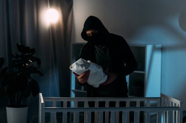 Maske ve beşik yakın dururken hoodie holding bebek çocuk kaçıran