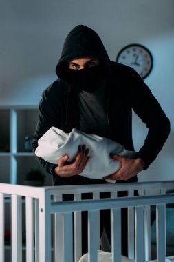 Siyah kıyafet ve maske holding bebek çocuk kaçıran