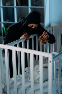 Alıkoyucu maskesi ve para çantası tutarak ve beşik içinde seyir siyah hoodie