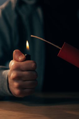Partial view of man holding lighter and igniting dynamite  clipart