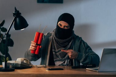 Masada oturan ve dinamit, parmağınızla işaret maskesi kızgın terörist