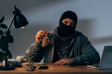 Masada oturan ve küçük ihale dolar ile siyah maskeli üzgün ceza