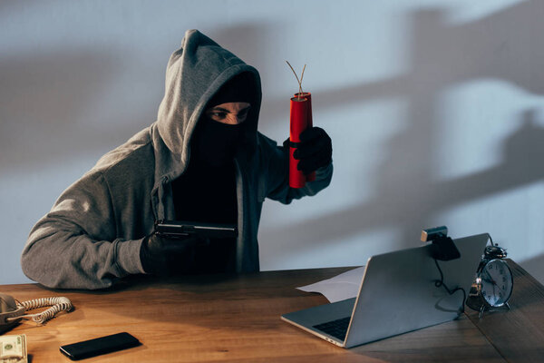 Террорист в черной маске с динамитом, нацеленным на веб-камеру
