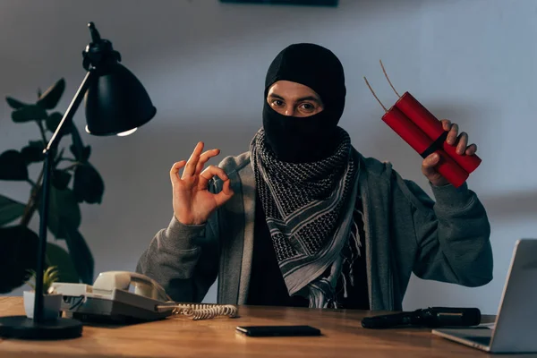 Terrorist in Maske hält Dynamit in der Hand und zeigt Okay-Zeichen im Zimmer — Stockbild Terrorist Maske Hält Dynamit Der Hand Und Zeigt Okay Zeichen — Stockfoto