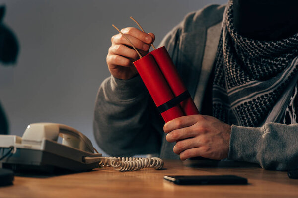 Cropped view of man holding dynamite at table in room