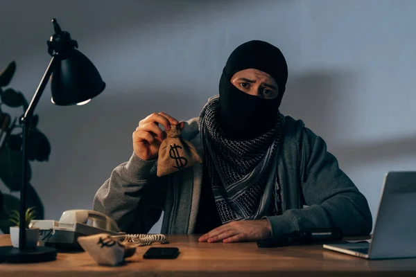 Triste Criminoso Máscara Preta Sentado Mesa Segurando Pequeno Saco Com — Fotografia de Stock