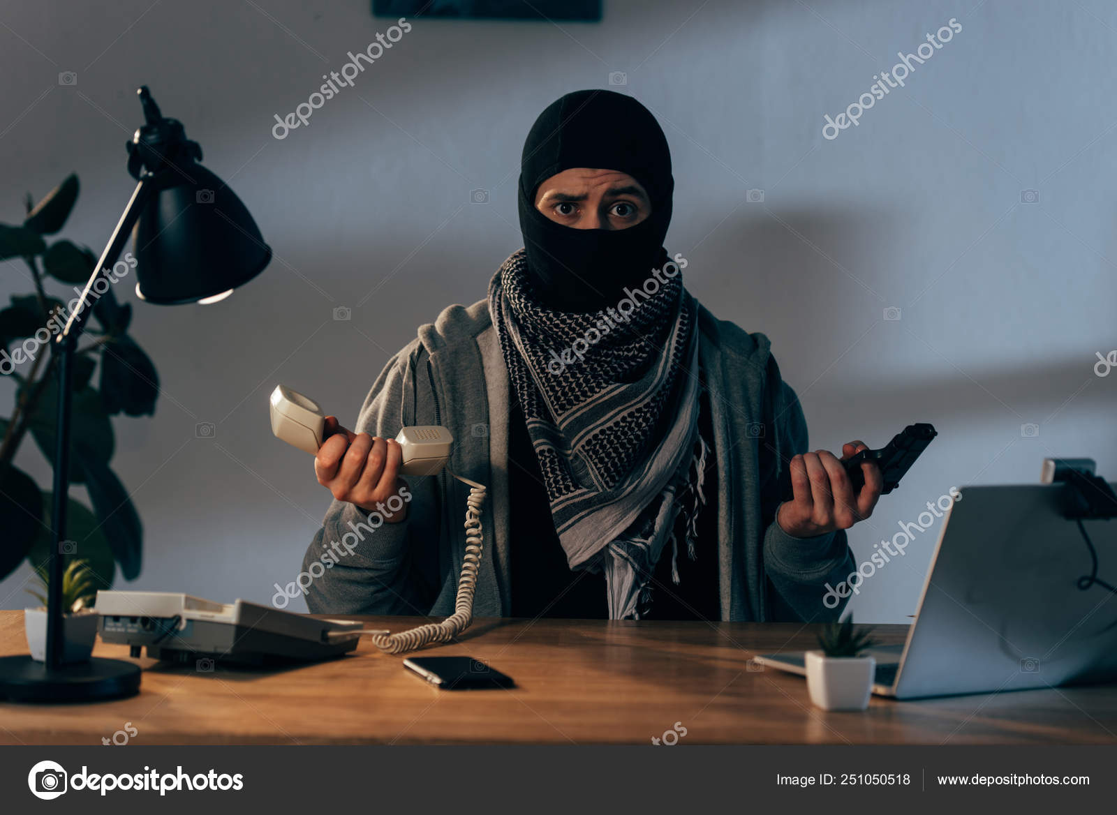Herunterladen - Enttäuschter Terrorist in Maske mit Waffe und Telefonhörer — Stockbild Enttäuschter Terrorist Maske Mit Waffe Und Telefonhörer — Stockfoto