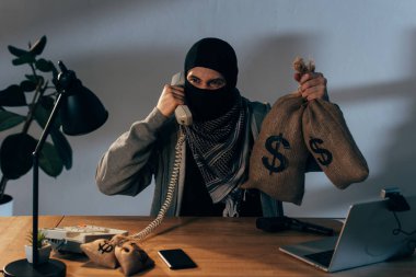 Para çantaları dolar işareti ile tutarak ve telefonla konuşurken sinirli terörist