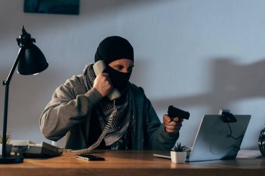 Telefonla konuşurken ve silah webcam gösterilen maskeli kızgın terörist