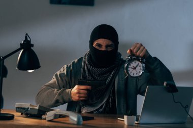 Saldırgan terörist silah ve çalar saat tutarak ve kameraya bakıyor