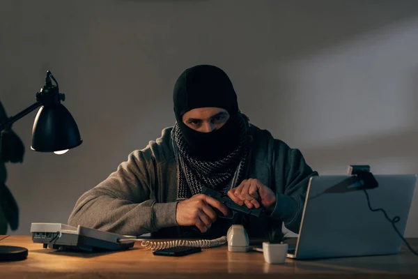 Terrorista Con Máscara Negra Sentado Mesa Cargando Pistola —  Fotos de Stock