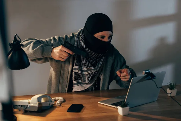 Aggressiver Krimineller zeigt mit Finger und zielt mit Waffe auf Laptop-Bildschirm — Stockbild Aggressiver Krimineller Zeigt Mit Finger Und Zielt Mit Waffe Auf — Stockfoto