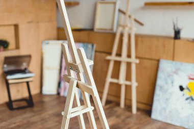 selective focus of wooden easel in painting studio clipart