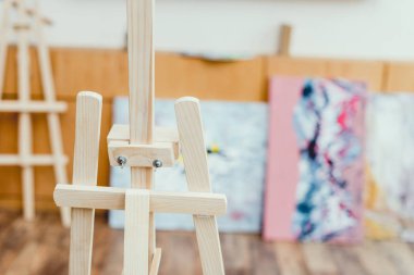 selective focus of wooden easel in painting studio clipart