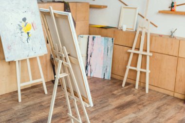 painting studio with wooden floor, cabinets, easels and paintings  clipart