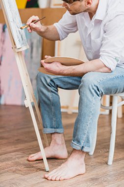 Kısmi yalınayak sanatçı beyaz gömlek ve mavi jeans tuval görünümünü