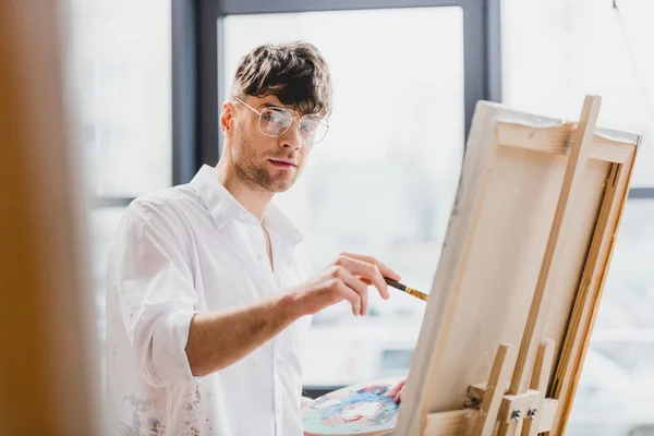 Selective Focus Handsome Artist Glasses Looking Camera While Drawing Canvas — Stock Photo, Image