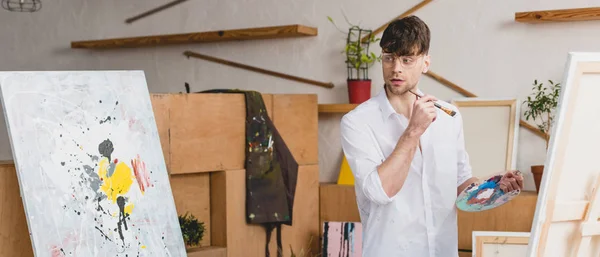 Plano Panorámico Artista Guapo Con Pincel Paleta Mirando Pintura Estudio — Foto de Stock