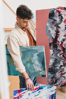 selective focus of artist holding multicolored abstract paintings clipart