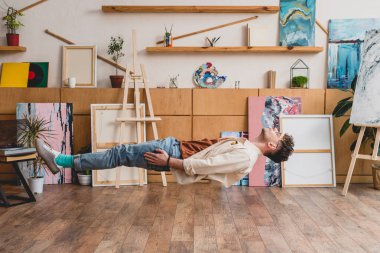 Kapalı gözlerle resim Studio ahşap zemin üzerinde levitating yakışıklı sanatçı