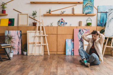 çapraz bacaklar ve baş resim Studio elleri ile katta oturan sanatçı
