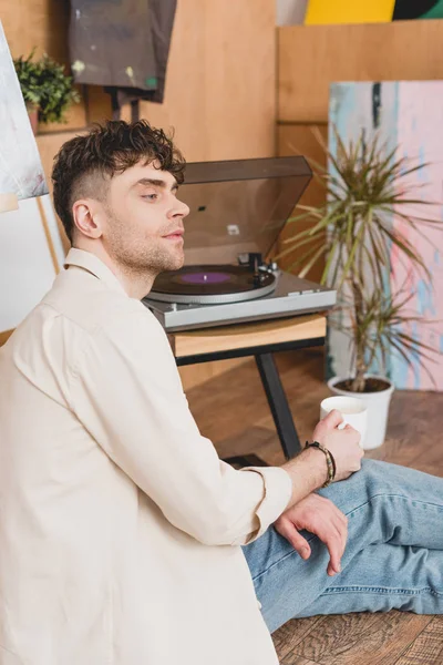 Dreamy Artist Holding Coffee Cup Looking Away While Sitting Vinyl — Stock Photo, Image