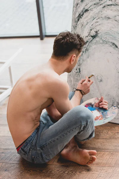 半裸艺术家坐在交叉的腿和画图片在画廊 — 图库照片
