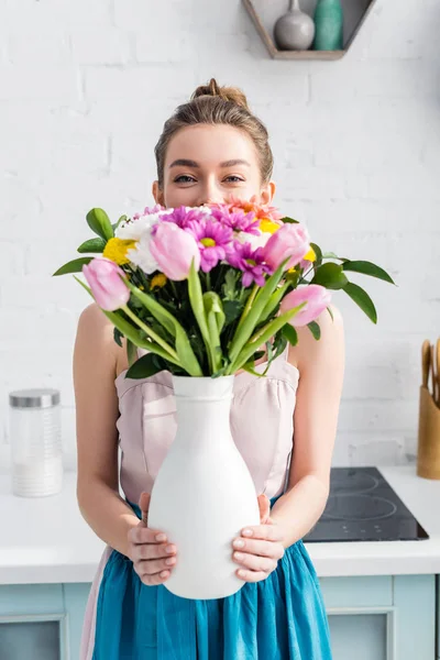 漂亮的女孩与模糊的脸躲在花瓶里的野花花束后面 — 图库照片