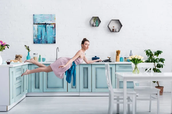エレガントなドレスとエプロン キッチンでパンと空気浮上の美しい裸足少女 — ストック写真