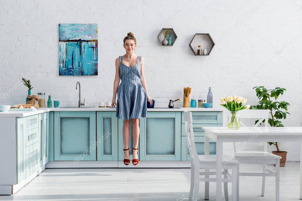 smiling pretty girl levitating in air in turquoise and white kitchen 