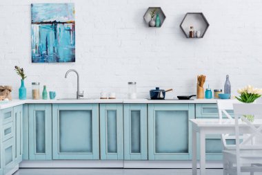 interior of modern turquoise kitchen with painting on white brick wall clipart