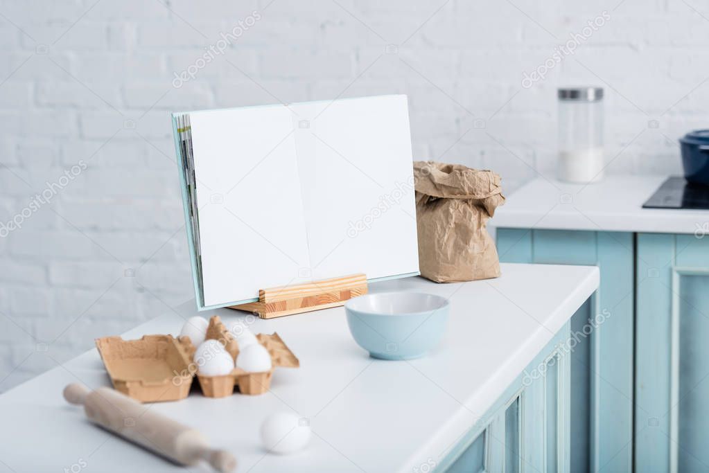 blank opened cookbook on table with cooking utensils and bakery ingredients