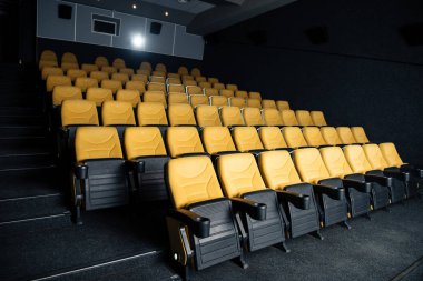 dark cinema hall with comfortable empty seats with cup holders clipart