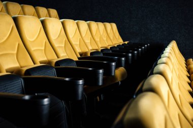 selective focus of comfortable orange cinema seats with cup holders clipart