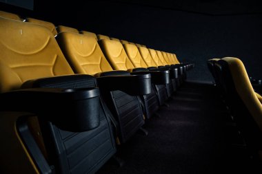 selective focus of orange seats with cup holders in cinema hall clipart