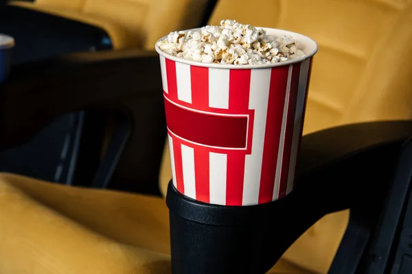 カップ ホルダーにポップコーンのストリップの紙コップと映画館の座席の選択と集中 — ストック写真