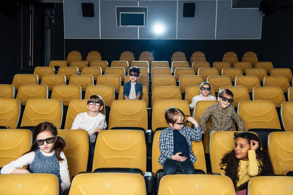 cute children in 3d glasses sitting in cinema hall together 