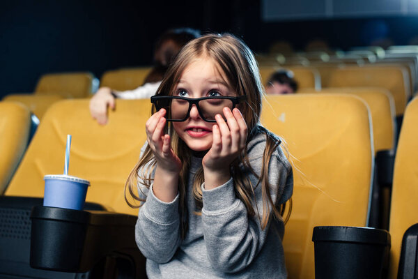 cute scared child in 3d glasses looking movie in cinema 