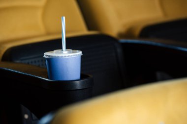 selective focus of cinema seat with blue disposable cup in cup holder  clipart