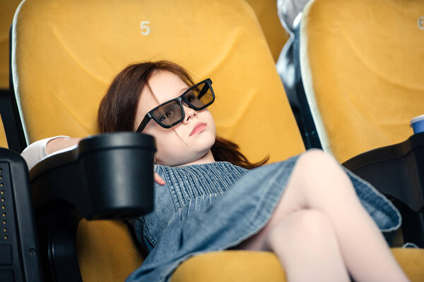 selective focus of dreamy child in 3d glasses sitting in cinema seat
