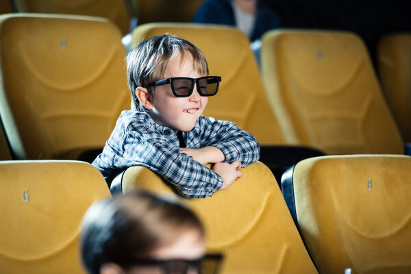 selective focus of smiling adorable boy in 3d glasses watching movie in cinema
