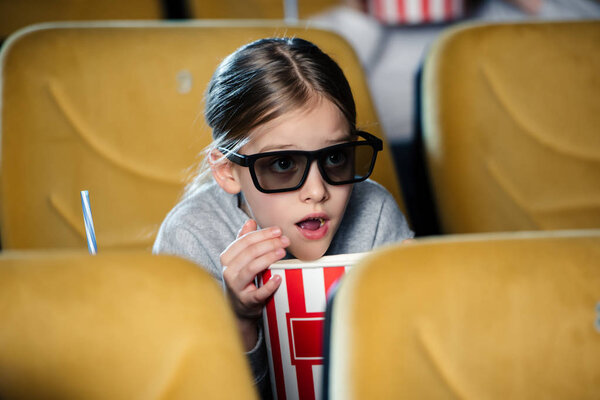 selective focus of frightened child in 3d glasses watching movie and eating pop corn